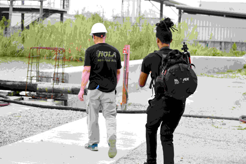 Two men walking side by side on a sidewalk, one carrying a backpack.